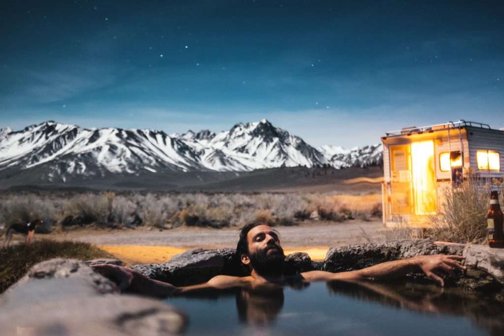 young man sitting in a hot springs while RV camping